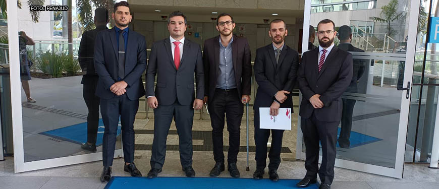 Representantes sindicais estão lado a lado em frente à entrada do CNJ (Conselho Nacional de Justiça), em Brasília, eles estão em trajes sociais e com semblante sério. Entre os sindicalistas estão Alexandre Pires, coordenador-geral e Felipe Rodrigues, diretor Financeiro, ambos do SINJUS-MG.