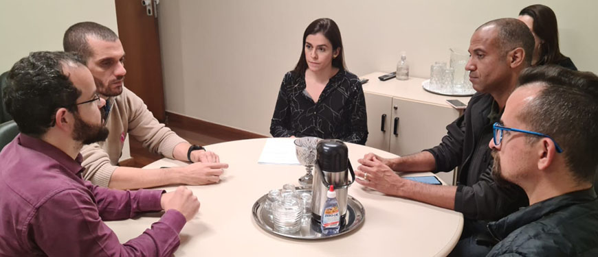 Sentados ao redor de uma mesa redonda estão Felipe Rodrigues, Alexandre Pires, Lohanna França, Wagner Ferreira e Alexandre Gomes