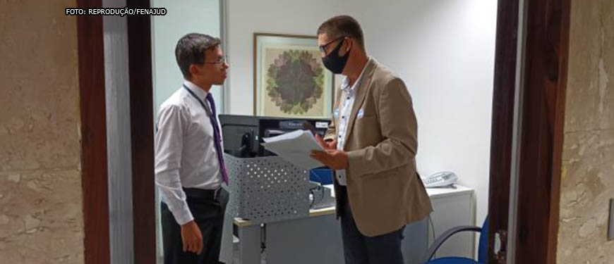 Foto de 2 homens em um escritório, conversando próximo a porta. Conteúdo Textual: Luta. Em atuação no Senado, Fenajud busca senadores para pedir aprovação do PL 4/22.