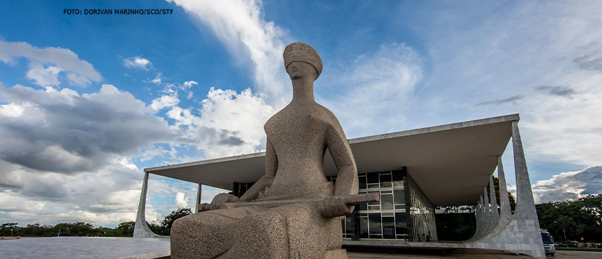 Fachada do Edifício do Supremo Tribunal Federal em Brasília, no primeiro plano há uma grande escultura da deusa Themis da Justiça.