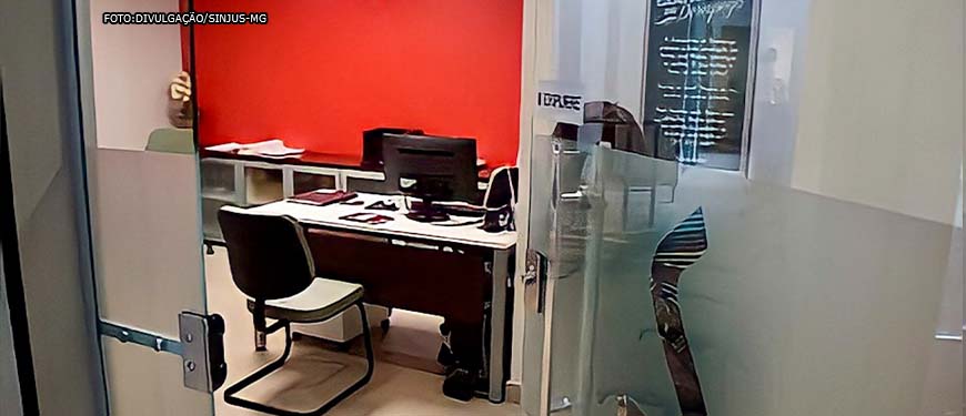 porta de vidro entreaberta da sede do SINJUS mostrando uma cadeira e uma mesa de atendimento da recepção.