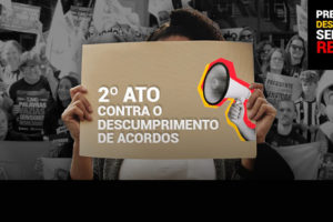 A imagem mostra uma pessoa segurando um cartaz que diz "2º ATO CONTRA O DESCUMPRIMENTO DE ACORDOS" em letras brancas. No cartaz, há a ilustração de um megafone. Ao fundo, várias pessoas estão em uma manifestação, segurando faixas e cartazes, muitos deles parcialmente visíveis. No canto superior direito, há um texto em fundo preto que diz: "PRESIDENTE DESCUMPRIU, SERVIDOR REAGIU!" com "DESCUMPRIU" em amarelo e "REAGIU!" em vermelho.