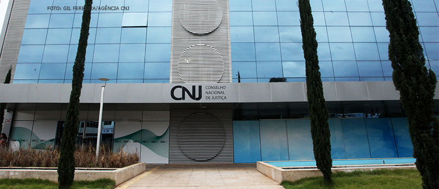 Foto da fachada da sede do Conselho Nacional de Justiça. Um prédio revestido com janelas espelhadas e um adereço central com formas circulares. Conteúdo textual: Consulta pública. Servidores podem opinar sobre Metas do Judiciário para 2023 até o dia 23/10.