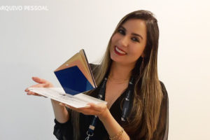 Foto da filiada Priscila Pereira de Souza, segurando seu prêmio de inovação do judiciário.