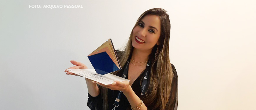 Foto da filiada Priscila Pereira de Souza, segurando seu prêmio de inovação do judiciário.