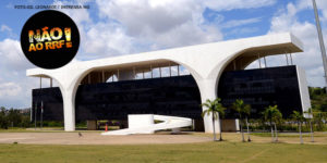 Foto da fachada da Cidade Administrativa com uma aplicação redonda "Não ao RRF!". Conteúdo Textual: #NAOAORRF REDUÇÃO DO DÉFICIT E AUMENTO DE RECEITAS CONFIRMAM QUE RRF DE ZEMA NÃO ERA NECESSÁRIO