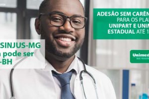 #ImagemAcessível: Médico negro segura papeis sorrindo em ambiente hospitalar.