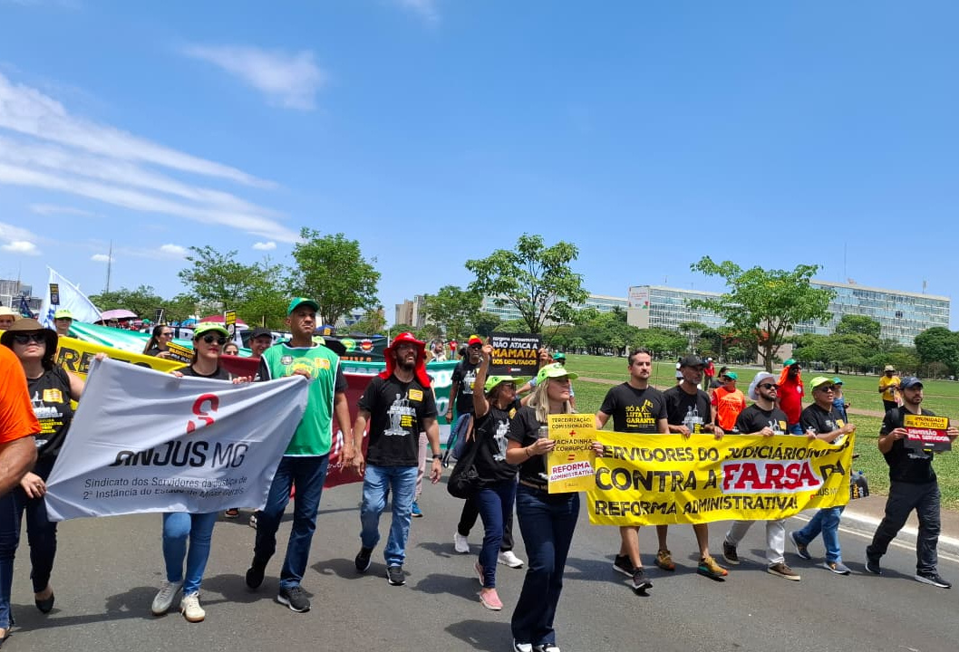  Dirigentes e filiados do SINJUS participam de manifestação na esplanada dos Ministérios em Brasília. Duas faixas estão em destaque: uma branca com o logotipo do SINJUS-MG e os dizeres “Sindicato dos Servidores da 2ª Instância do Estado de Minas Gerais”, e outra amarela com a frase “Servidores do Judiciário contra a farsa da Reforma Administrativa”